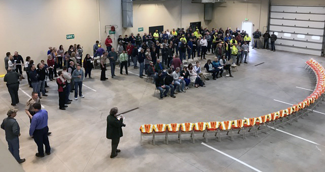 A room features a row of 35 empy chairs with yellow safety vests draped on them, symbolizing workers who have died on the job.